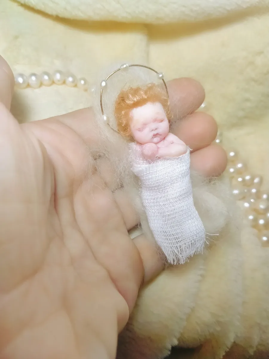 OOAK miniature baby doll with curly auburn hair in white swaddling blanket, held gently in palm with pearl beads - by Mini Baby Dolls