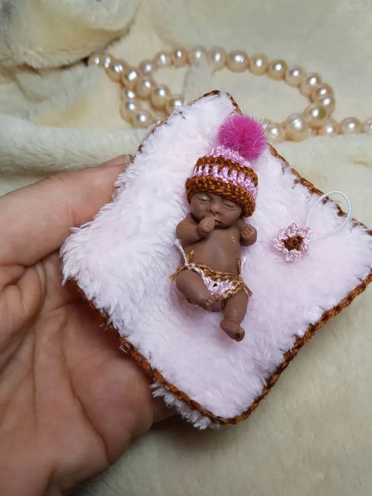 Sleeping OOAK miniature baby doll on white fluffy crocheted blanket, wearing brown and pink striped hat with pink pom pom, held in palm - by Mini Baby Dolls