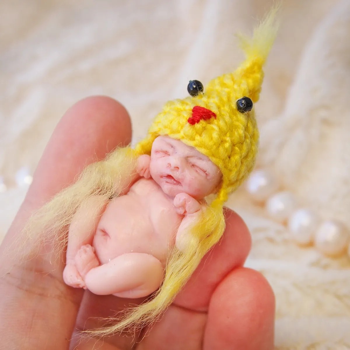 Adorable OOAK miniature chick baby doll in yellow crocheted hat with beak and feathery yellow outfit, held in palm - by Mini Baby Dolls