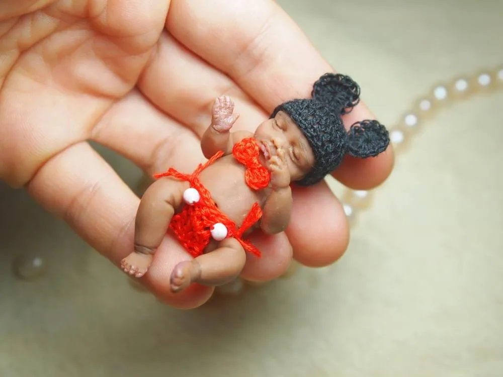 Playful OOAK miniature baby doll in Minnie Mouse inspired orange dress with black mouse ears, displayed in palm - by Mini Baby Dolls