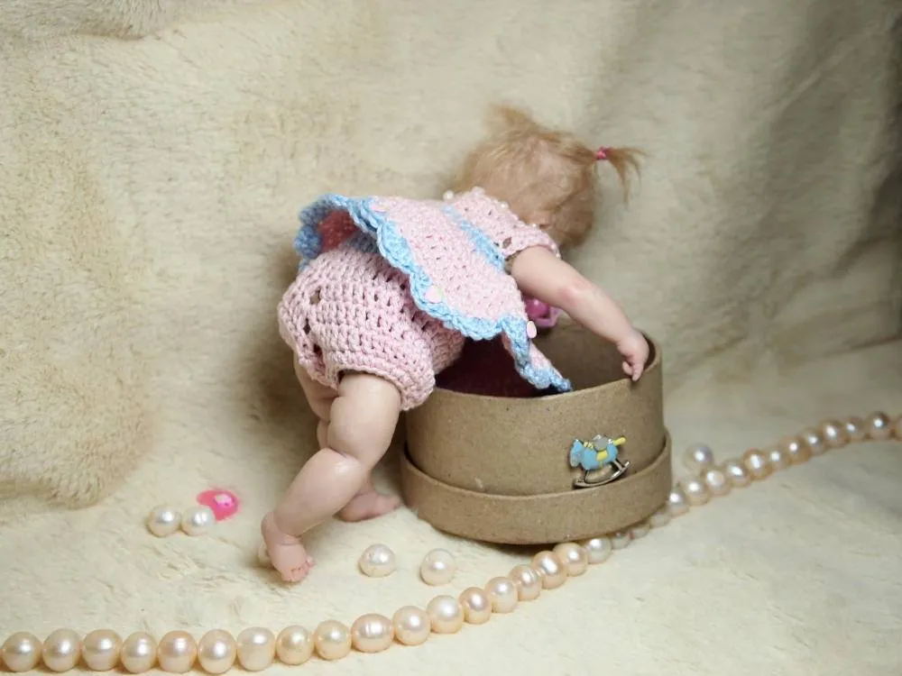 OOAK polymer clay miniature baby doll with blonde hair wearing a handmade pink and blue crocheted dress, posed with a vintage round keepsake box and pearl beads - by Mini Baby Dolls