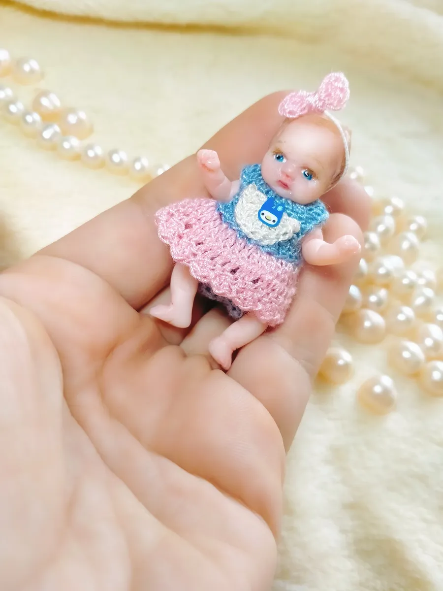 Adorable OOAK miniature baby doll in pink crocheted dress with bow headband, posed in palm with pearl beads - by Mini Baby Dolls