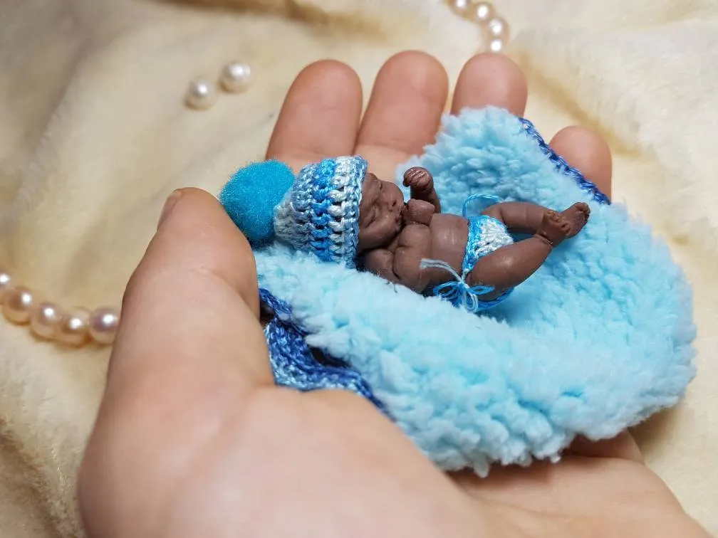 Sleeping OOAK miniature baby doll on fluffy blue crocheted pillow wearing a matching blue bonnet, held in palm with pearl beads - by Mini Baby Dolls