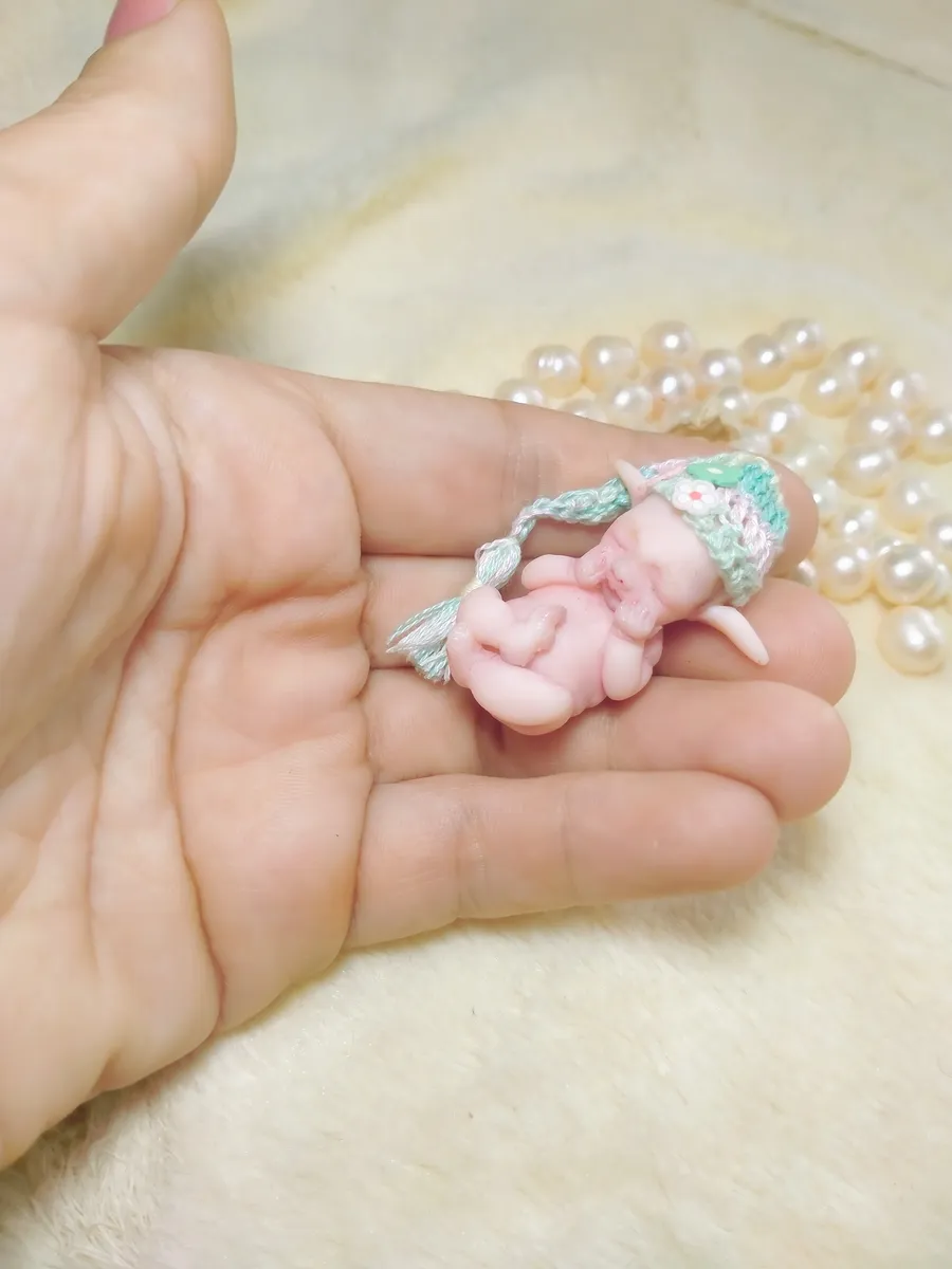 Sleeping OOAK miniature baby doll in mint green and white crocheted outfit, cradled in palm with pearl beads - by Mini Baby Dolls