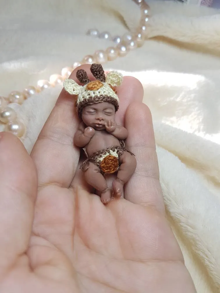 Sleeping OOAK miniature baby doll in adorable giraffe costume with spotted crocheted hat and brown details, displayed in palm with pearl beads - by Mini Baby Dolls