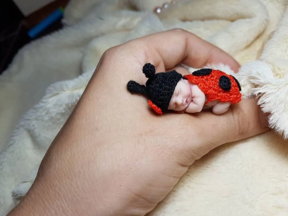 Sleeping OOAK miniature baby doll in adorable red and black crocheted ladybug costume with antennae, displayed with pearl beads - by Mini Baby Dolls