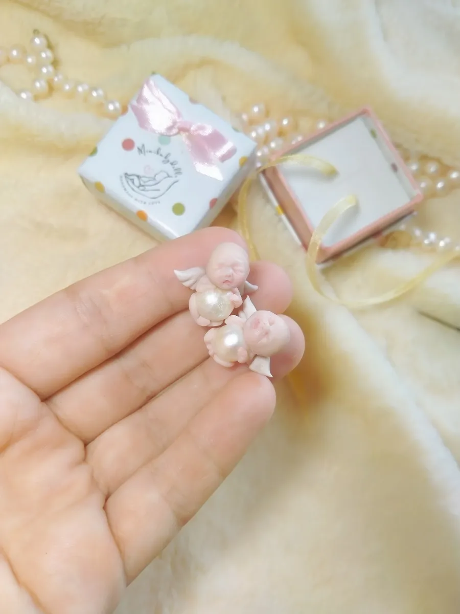 Tiny OOAK miniature angel baby doll with wings displayed in palm next to decorative gift box with pink bow - by Mini Baby Dolls