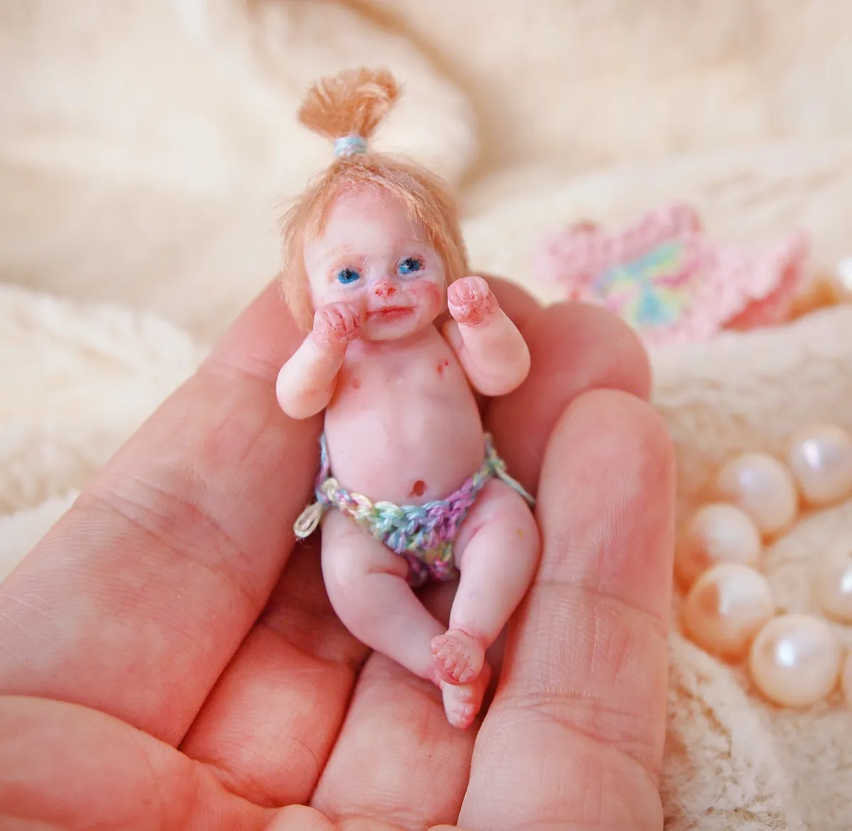 Tiny sleeping OOAK miniature baby doll nestled inside a golden walnut shell, an ultra-miniature collectible displayed with pearl beads - by Mini Baby Dolls