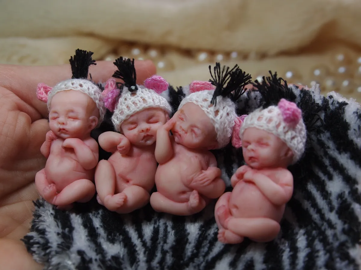 Three sleeping OOAK miniature baby dolls laying in a row, showcasing identical triplets with realistic features - by Mini Baby Dolls