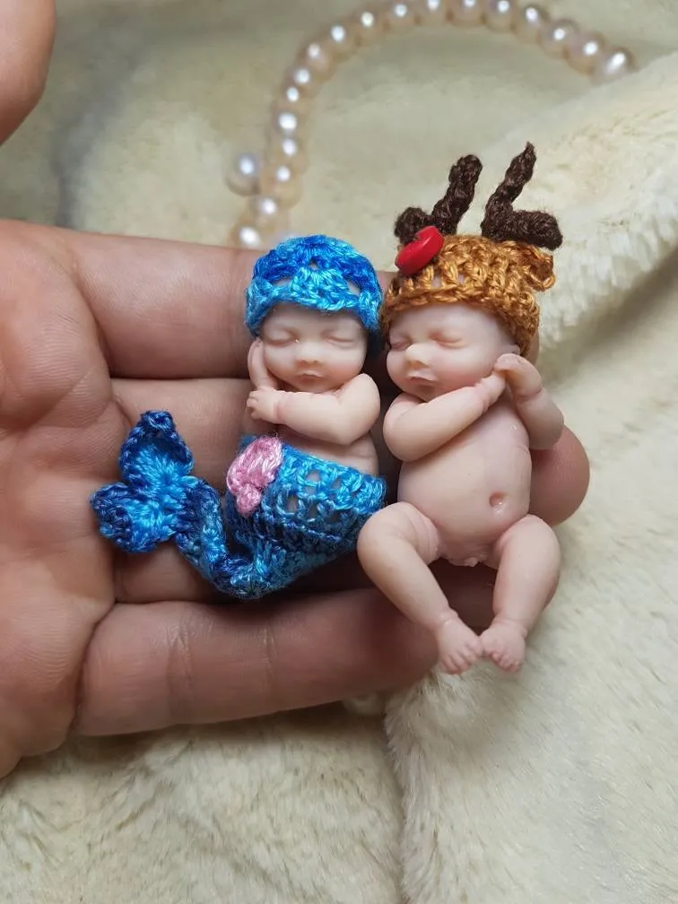 Two adorable OOAK miniature baby dolls together - one in blue crocheted outfit with reindeer hat, one in pink outfit with striped hat - by Mini Baby Dolls