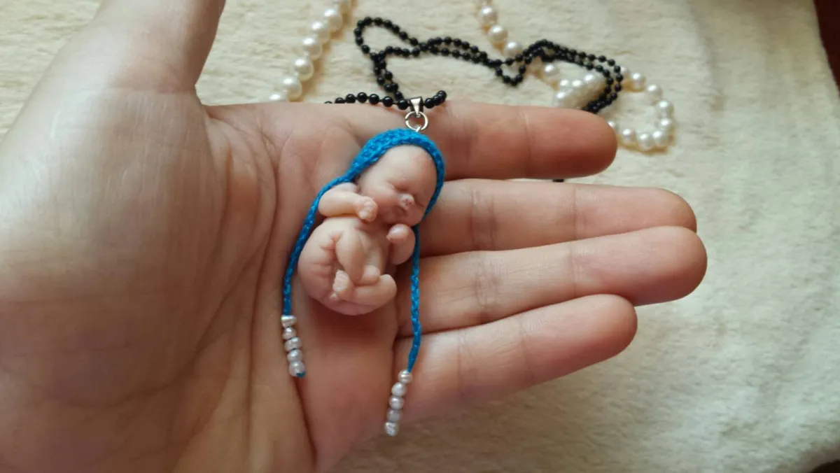 Sleeping OOAK miniature baby doll as wearable pendant necklace in blue crocheted outfit on black and pearl chain - by Mini Baby Dolls